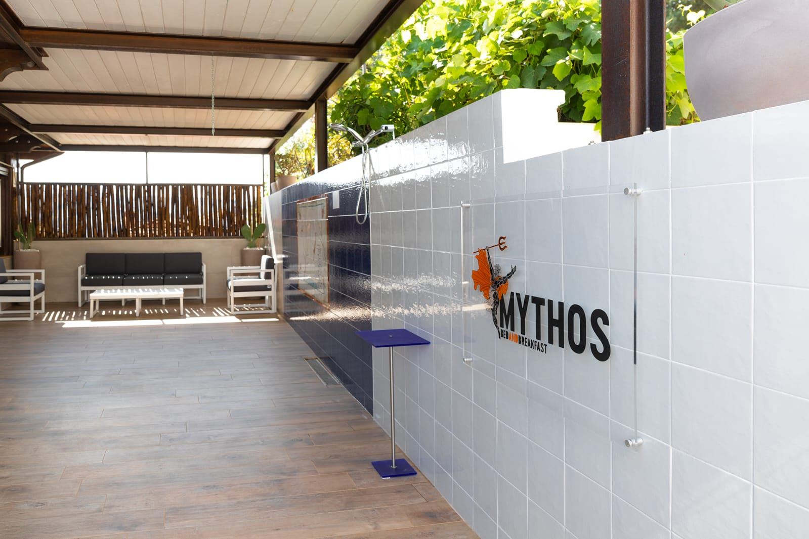 Dettaglio piastrelle in mosaico blu con logo Mythos sulla terrazza
